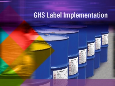 Line of barrels with text "GHS Label Implementation"